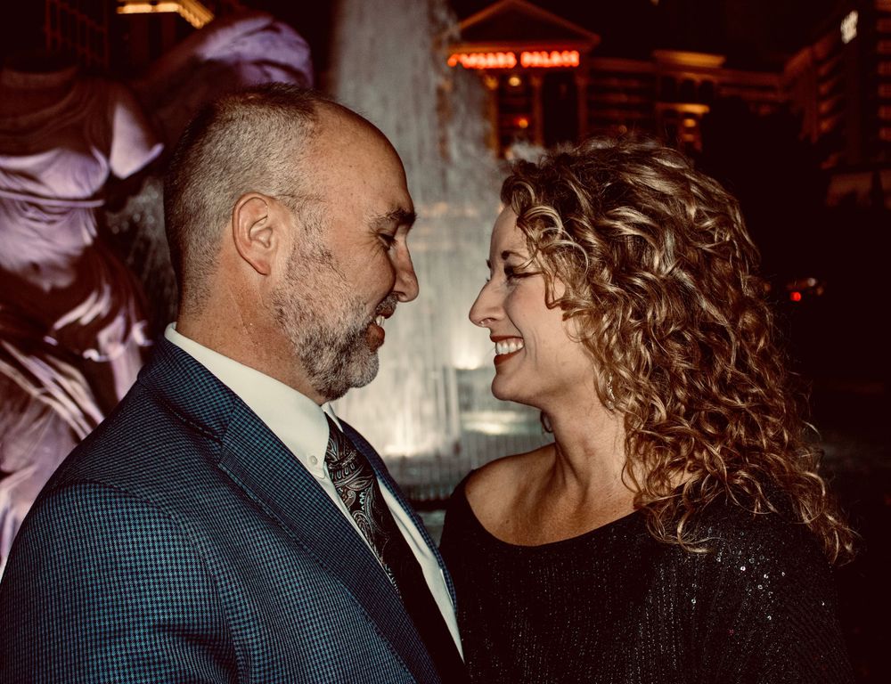 Couple gazing lovingly at each other near a fountain at night in Las Vegas.