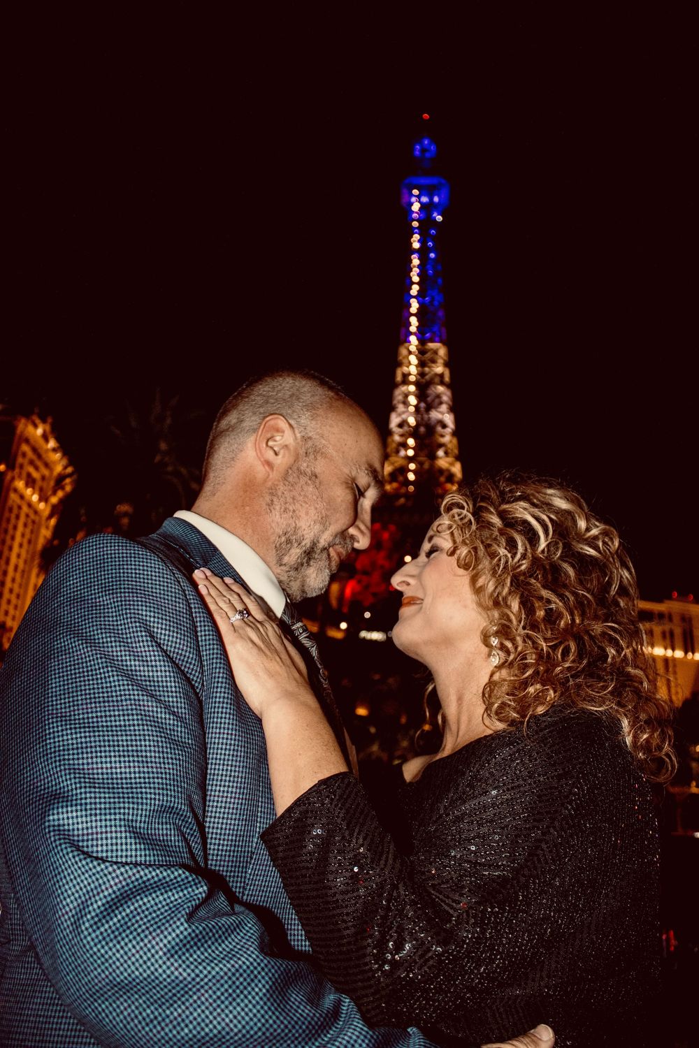 Couple gazing at each other with the Paris Las Vegas Eiffel Tower lit up behind them.