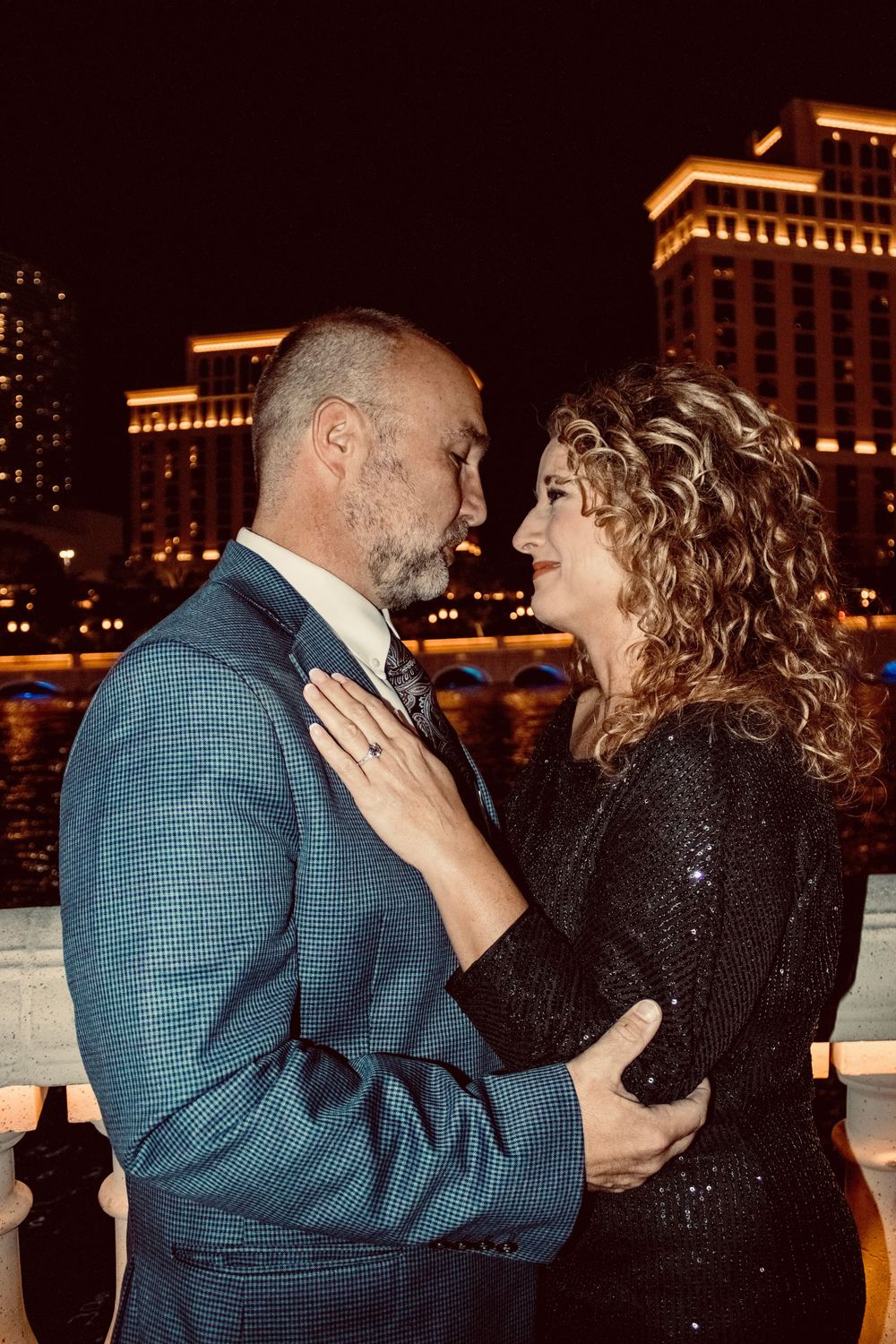 Couple in formal attire sharing an intimate embrace on the Las Vegas Strip at night.