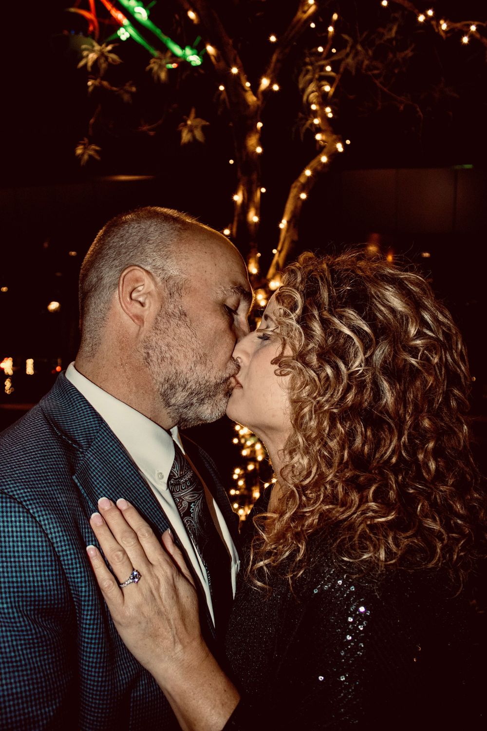 Couple sharing a kiss in front of twinkling lights on the Las Vegas Strip at night.