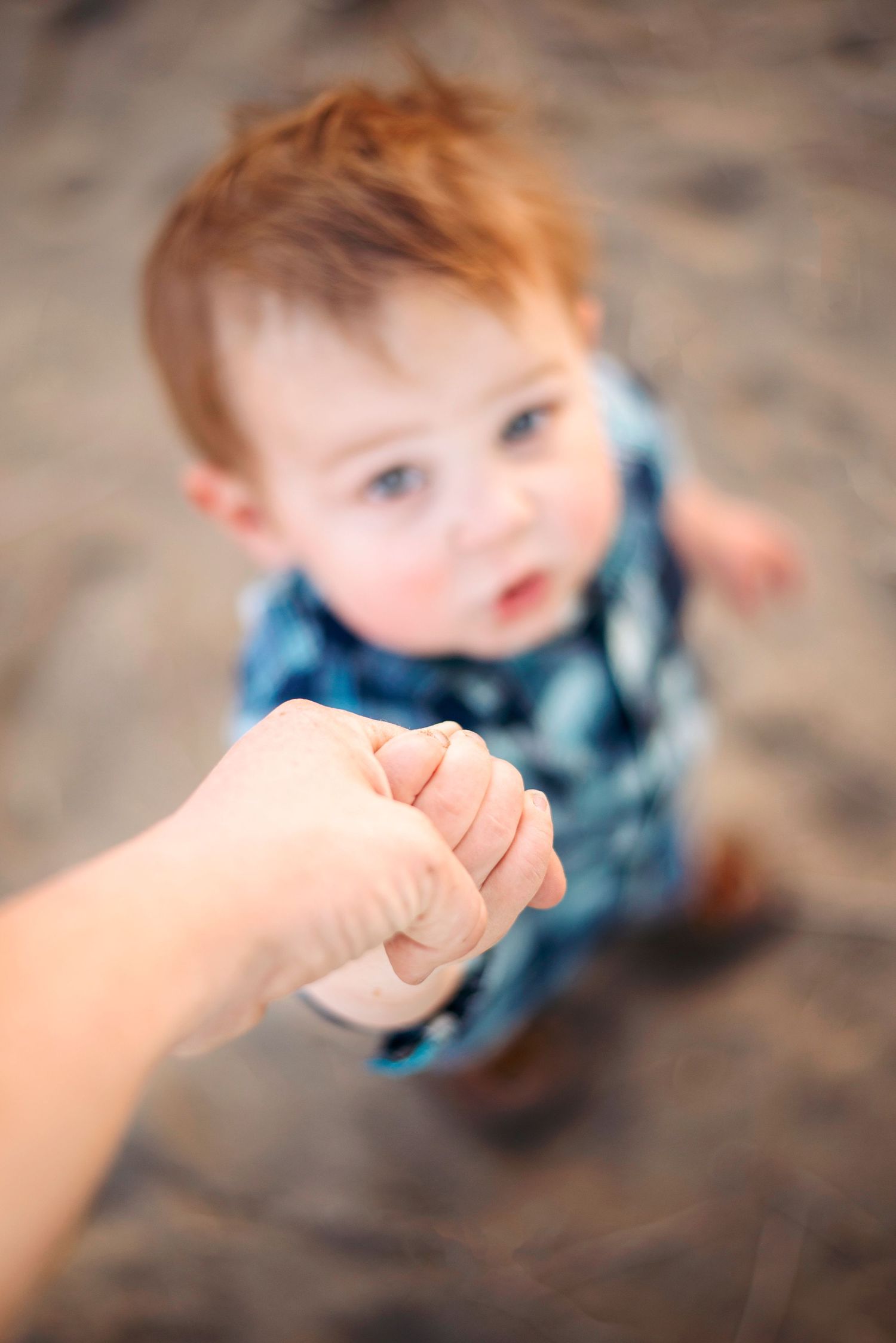 young boy holds mom's hand as he looks up at her family photography Ellensburg, WA
