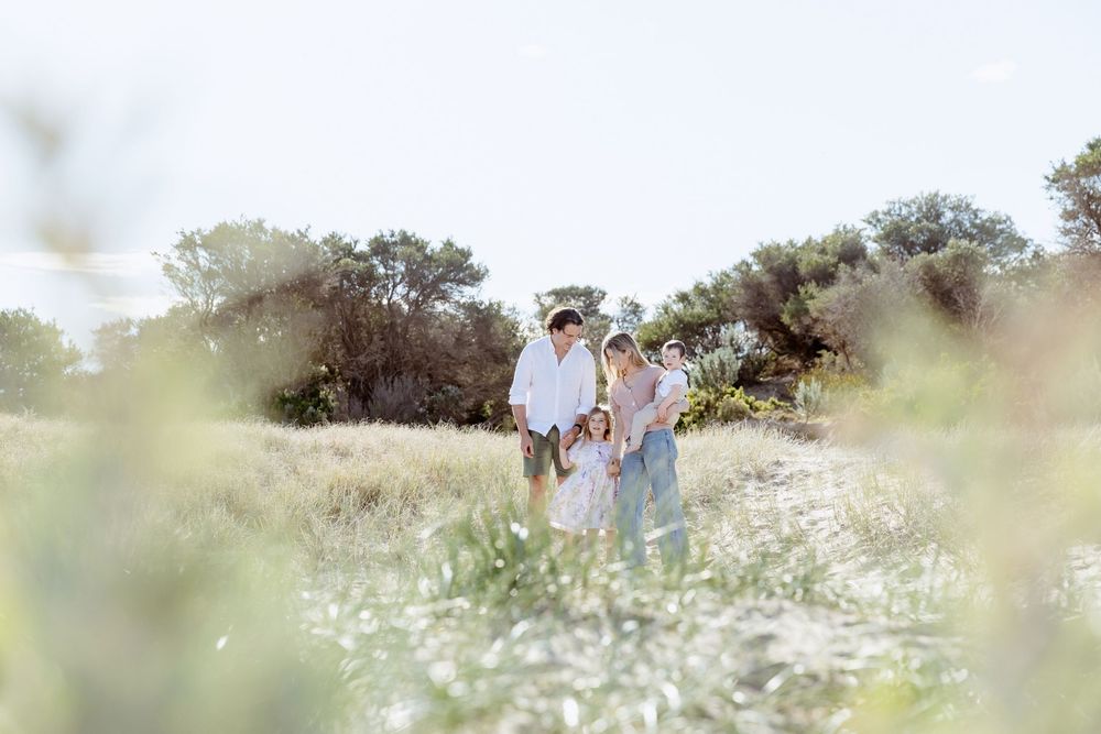 Dreamy panoramic view of a family walking through a blooming meadow with soft sunlit bokeh.