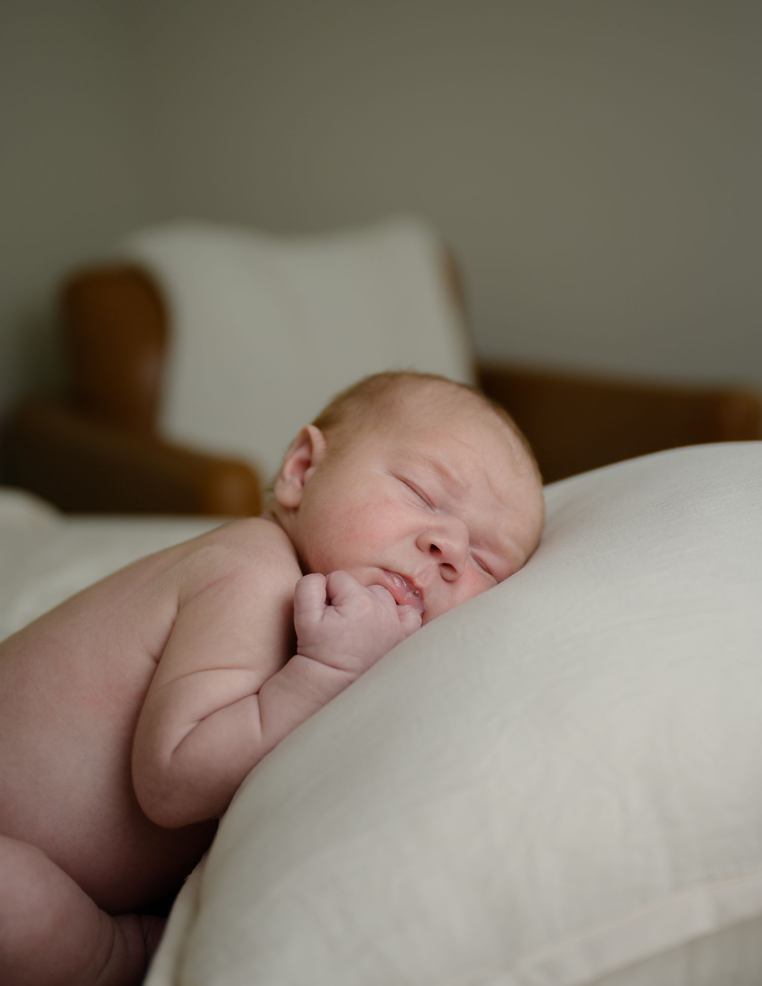 Sleeping newborn baby resting peacefully on white pillows.