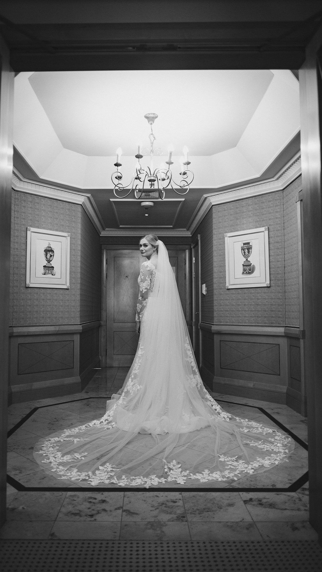 Stunning cathedral-length wedding dress train displayed in an elegant hallway with chandelier lighting.