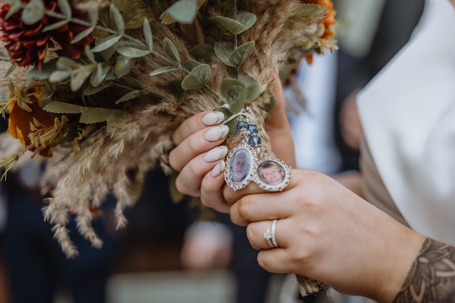 Autumn wedding bouquet with dried flowers and orange accents against a rustic backdrop.