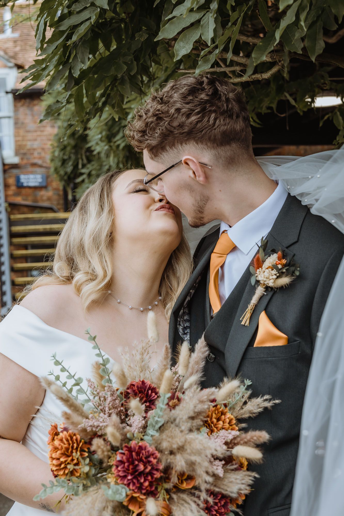 Fall wedding details featuring orange and burgundy floral arrangements with dried elements.