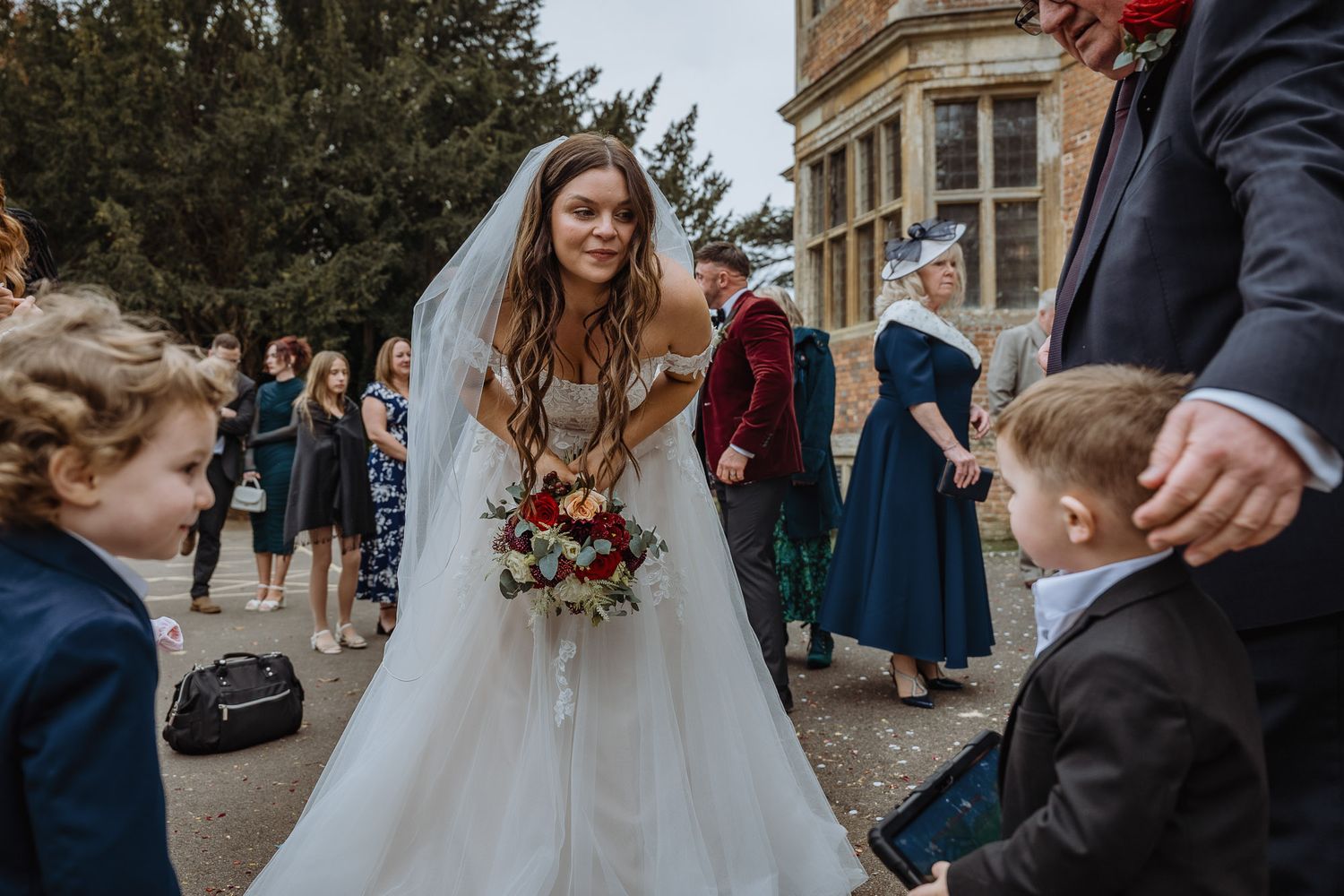 Wedding guests gather outside a historic stone building during an elegant outdoor ceremony.
