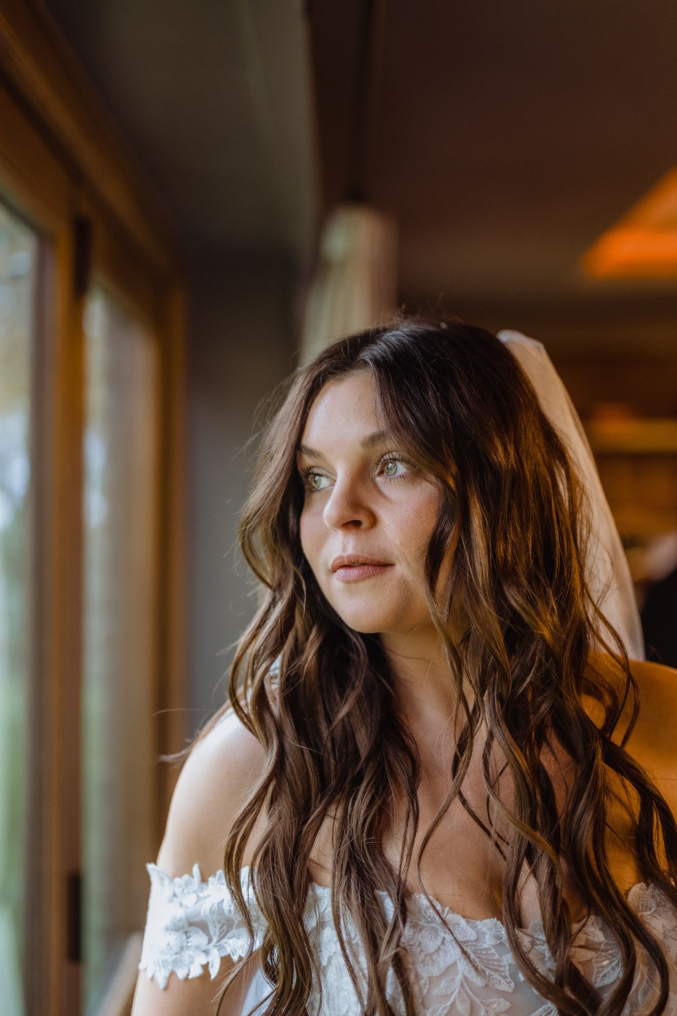 Soft natural light illuminates delicate lace details of a wedding dress.