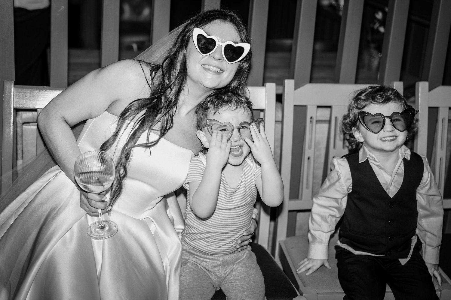 Black and white photo of wedding guests celebrating and dancing at a reception.