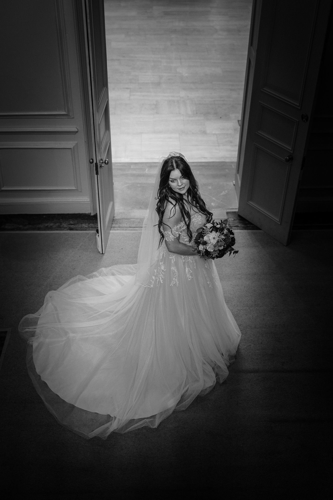 Dramatic black and white shot of a flowing wedding dress in an empty room.