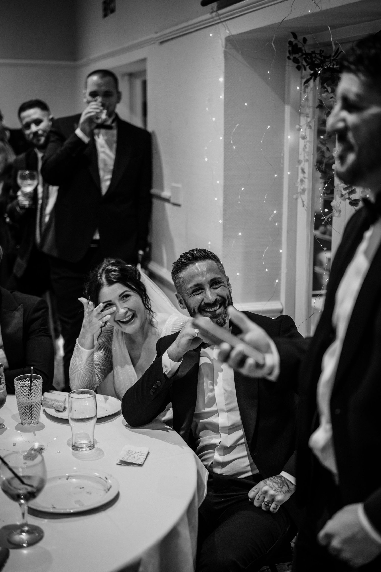 Wedding guests laughing together at a reception table.