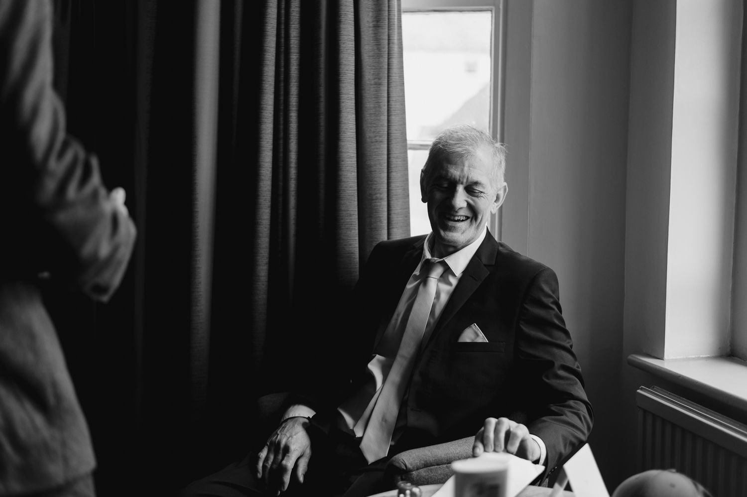 Wedding guests in formal attire reading programs during an indoor ceremony.