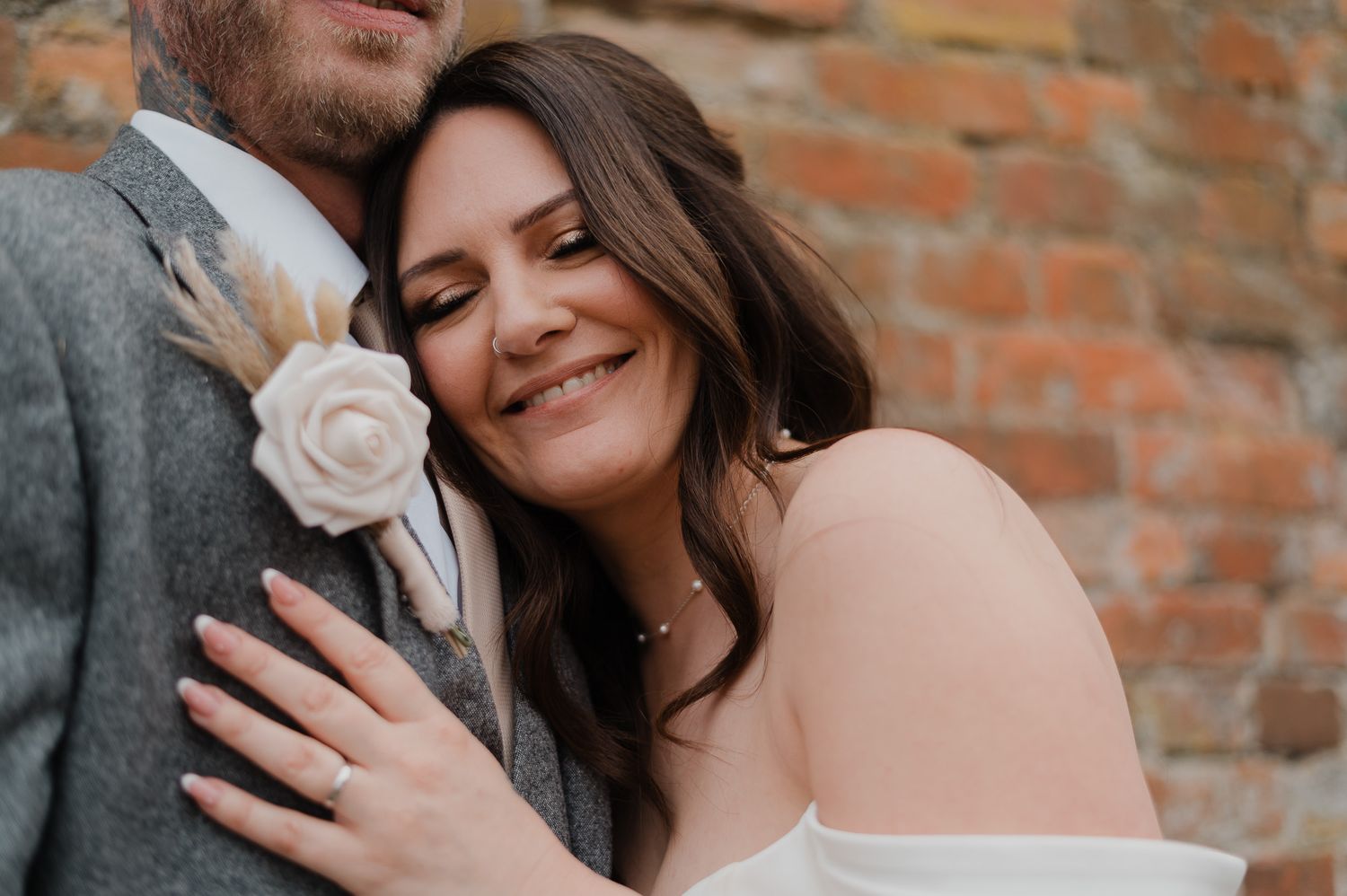 Close-up candid moments between newlyweds against textured brick background.