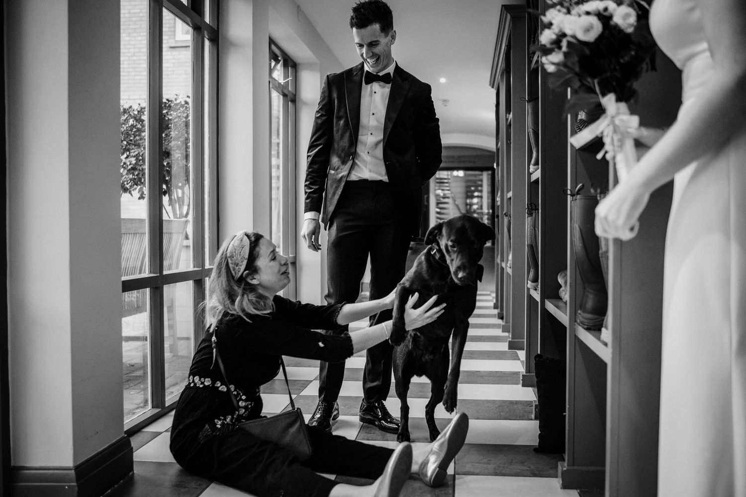 Black and white photo of wedding guests gathering in venue hallway.