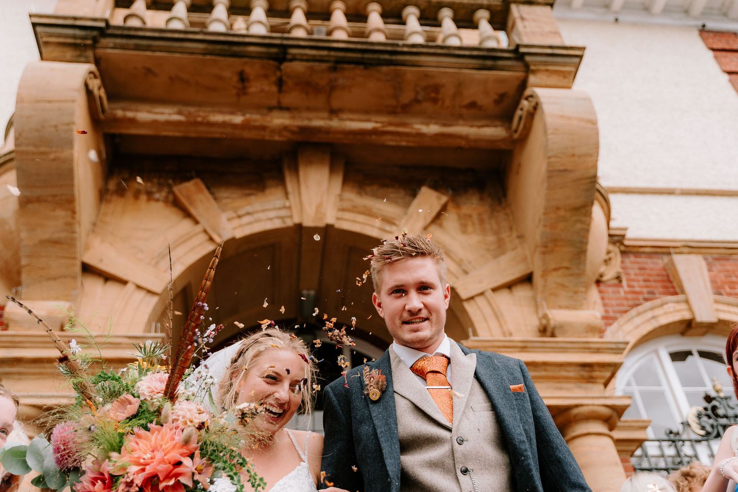 Wedding couple poses under ornate stone architecture with warm lighting.