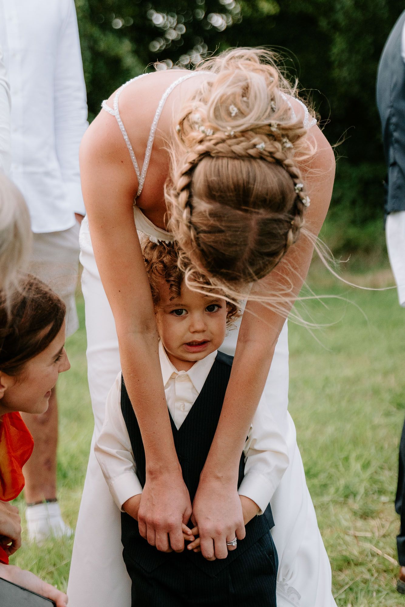 Wedding party plays outdoor games on grassy field during reception.