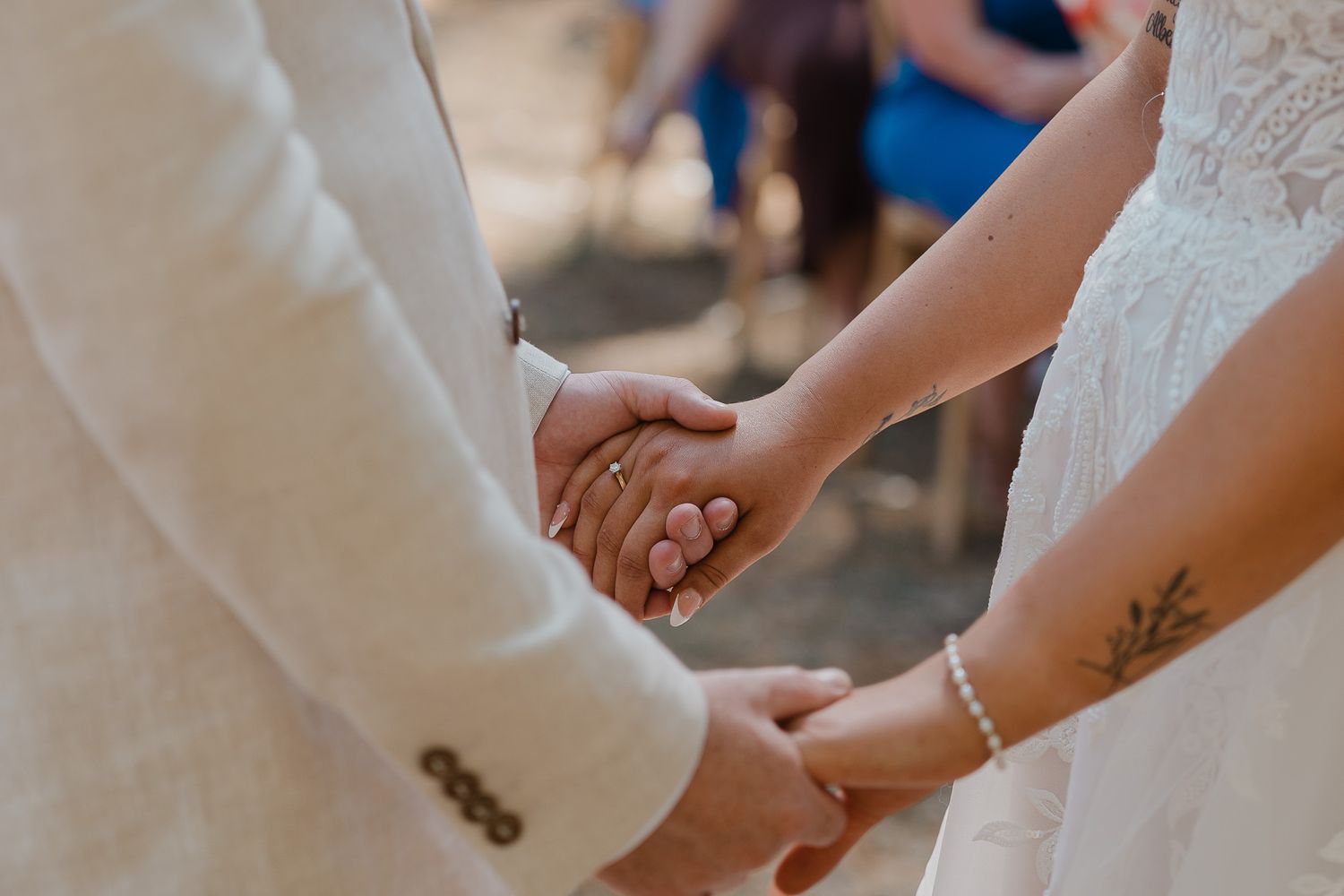Close-up of hands during wedding ceremony showing rings and lace details.