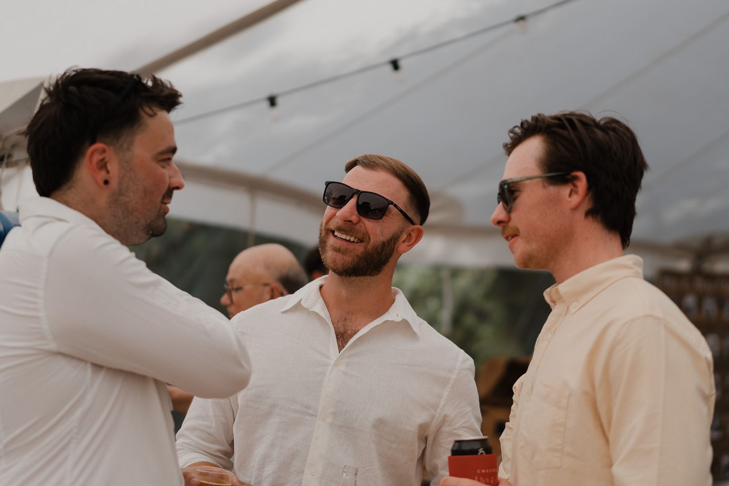Groomsmen in light colored suits share a moment outdoors.