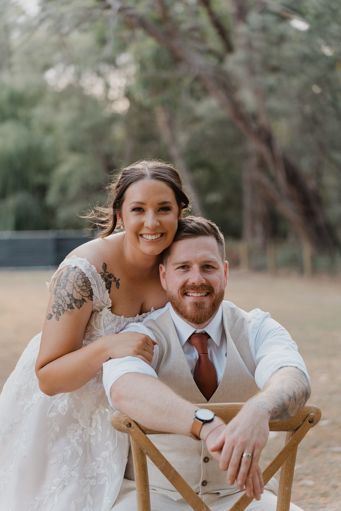 Couple shares intimate moments while seated in wooden chairs outdoors.