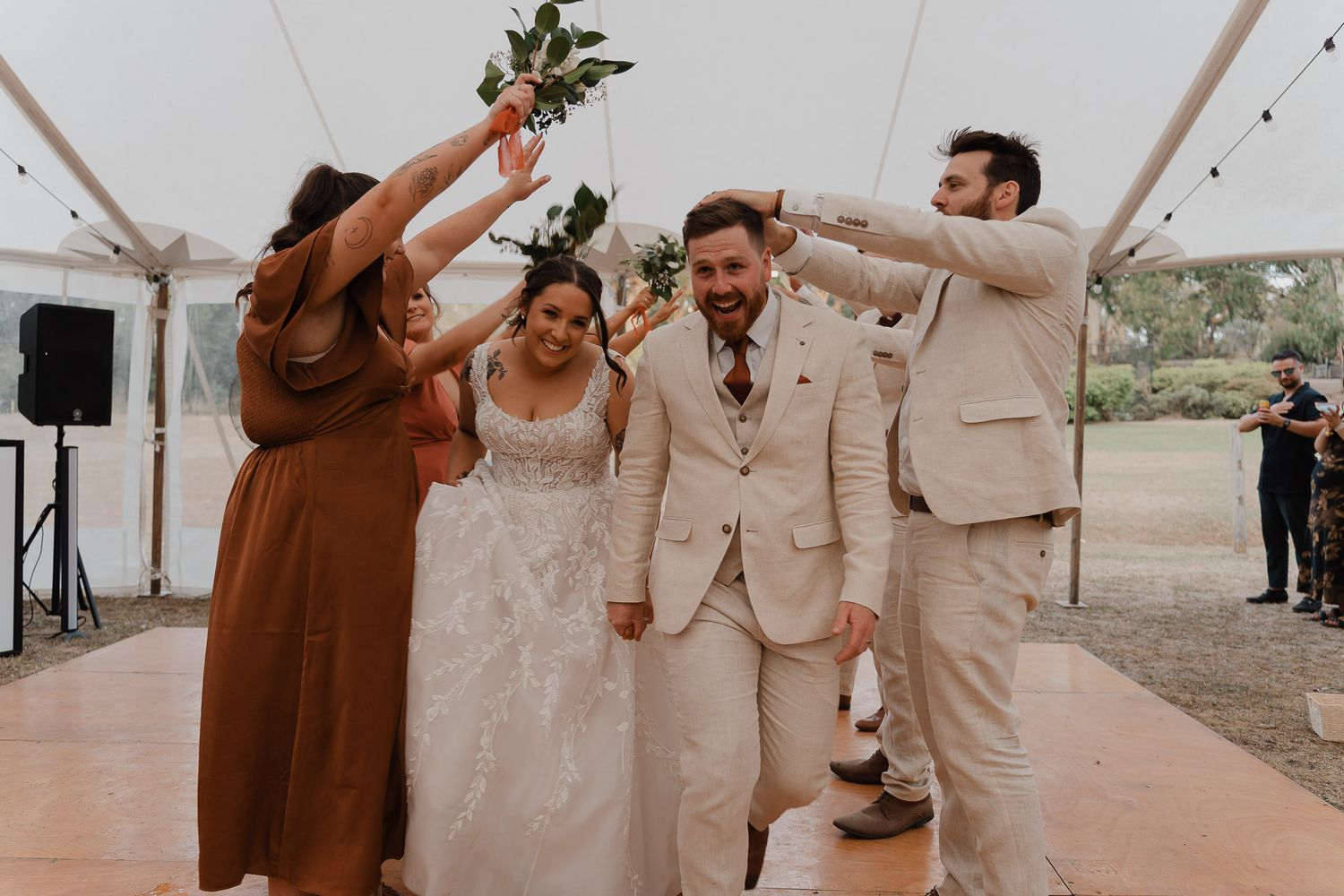 Wedding party celebrates with joyful dance moves in neutral toned attire.