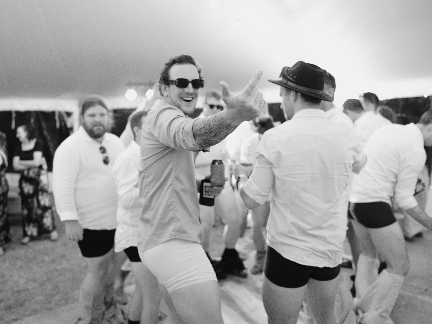 Wedding guests dance together in white attire at an outdoor reception celebration.