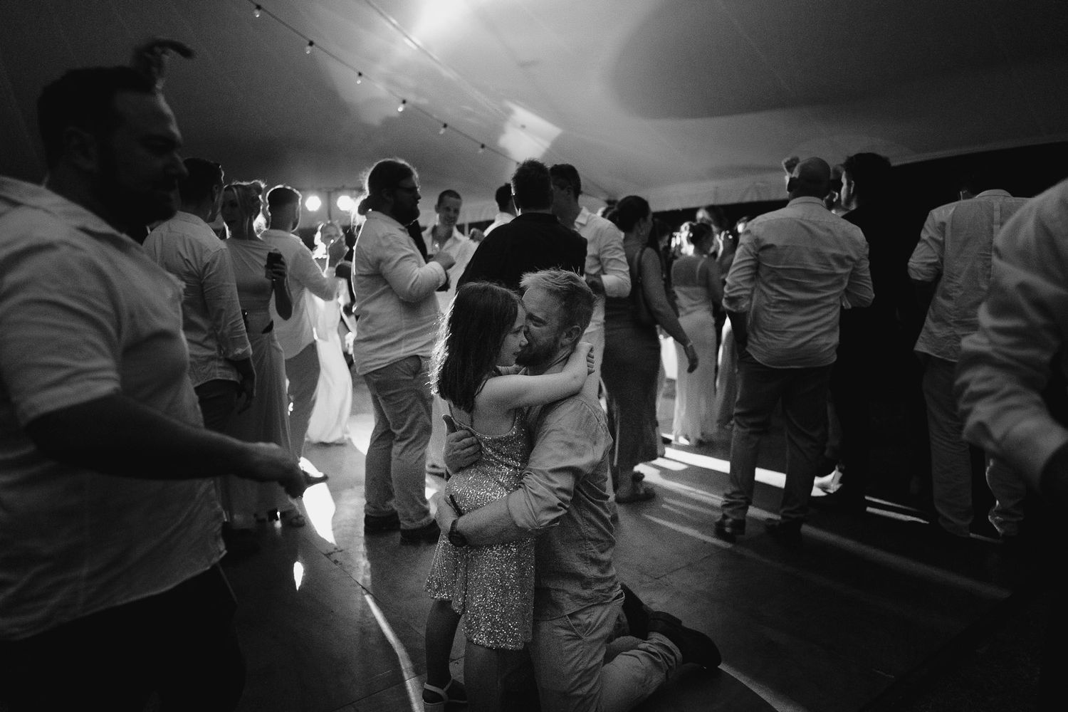 Silhouettes of people dancing at a dimly lit indoor celebration.