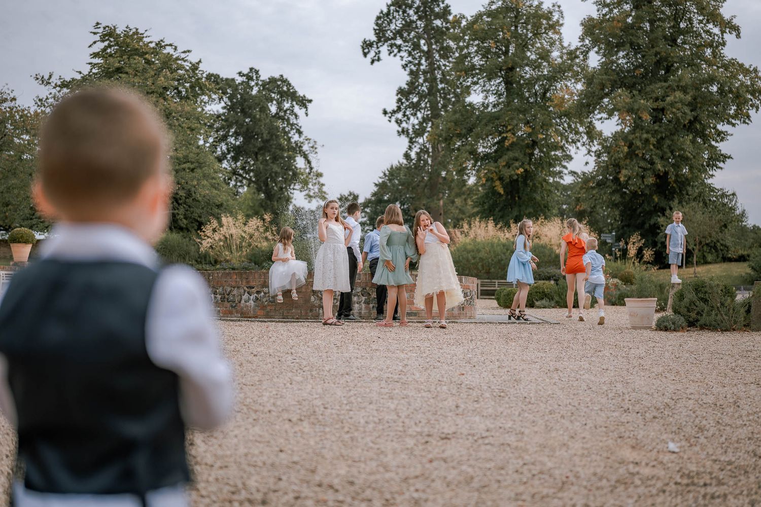Wedding guests gathering on a gravel path surrounded by trees.