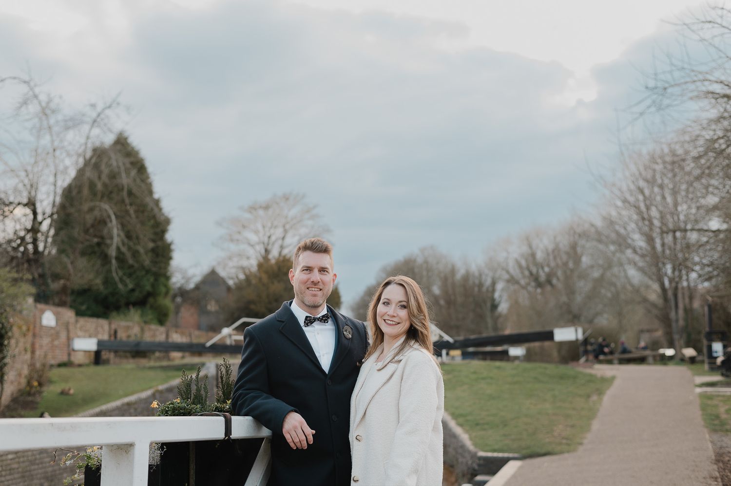 Couple walking together on a path with brick buildings in the background.