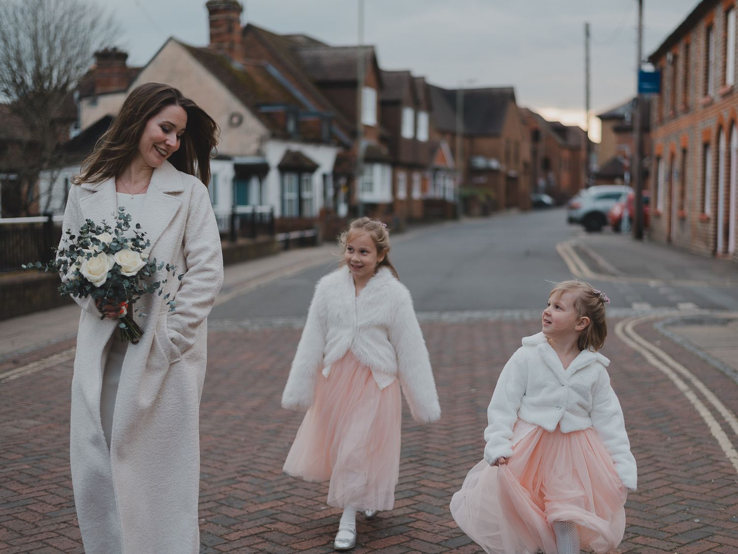 Family walking down a brick-paved street in winter clothing.