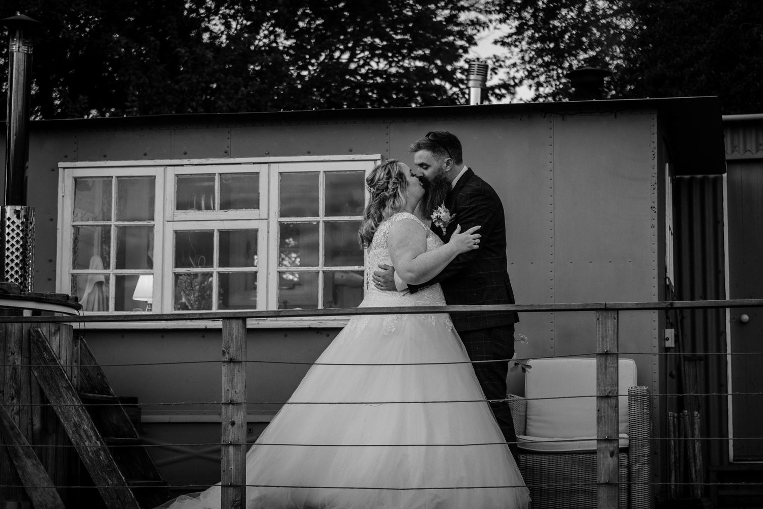 Silhouetted wedding couple embracing outside a building at dusk.