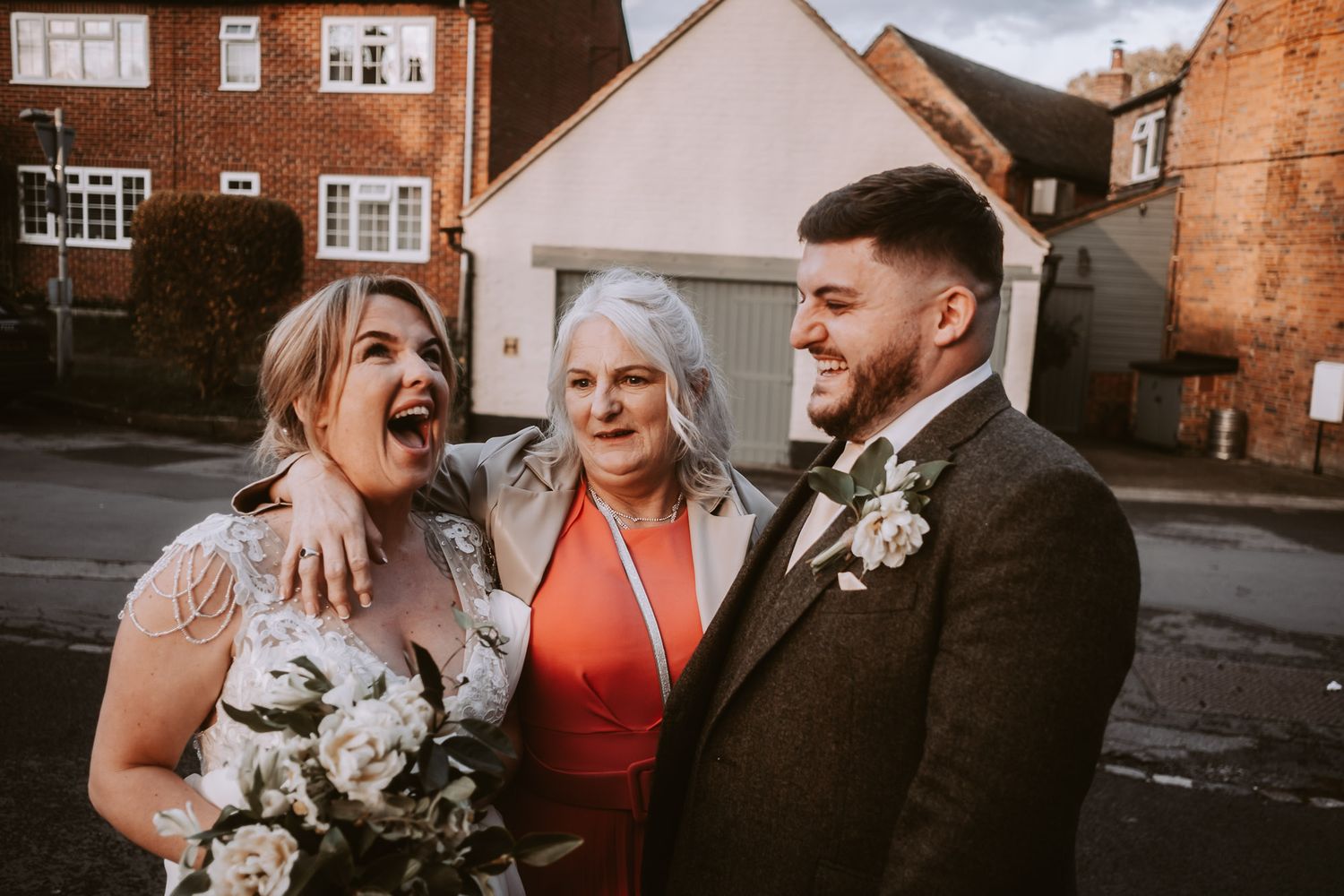 Wedding party posing together on a residential street with brick houses.