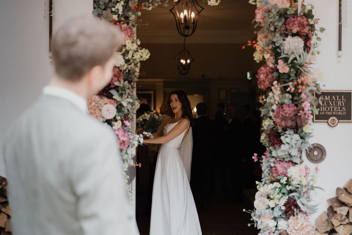 Elegant floral arch with pink and white blooms frames a wedding ceremony space.