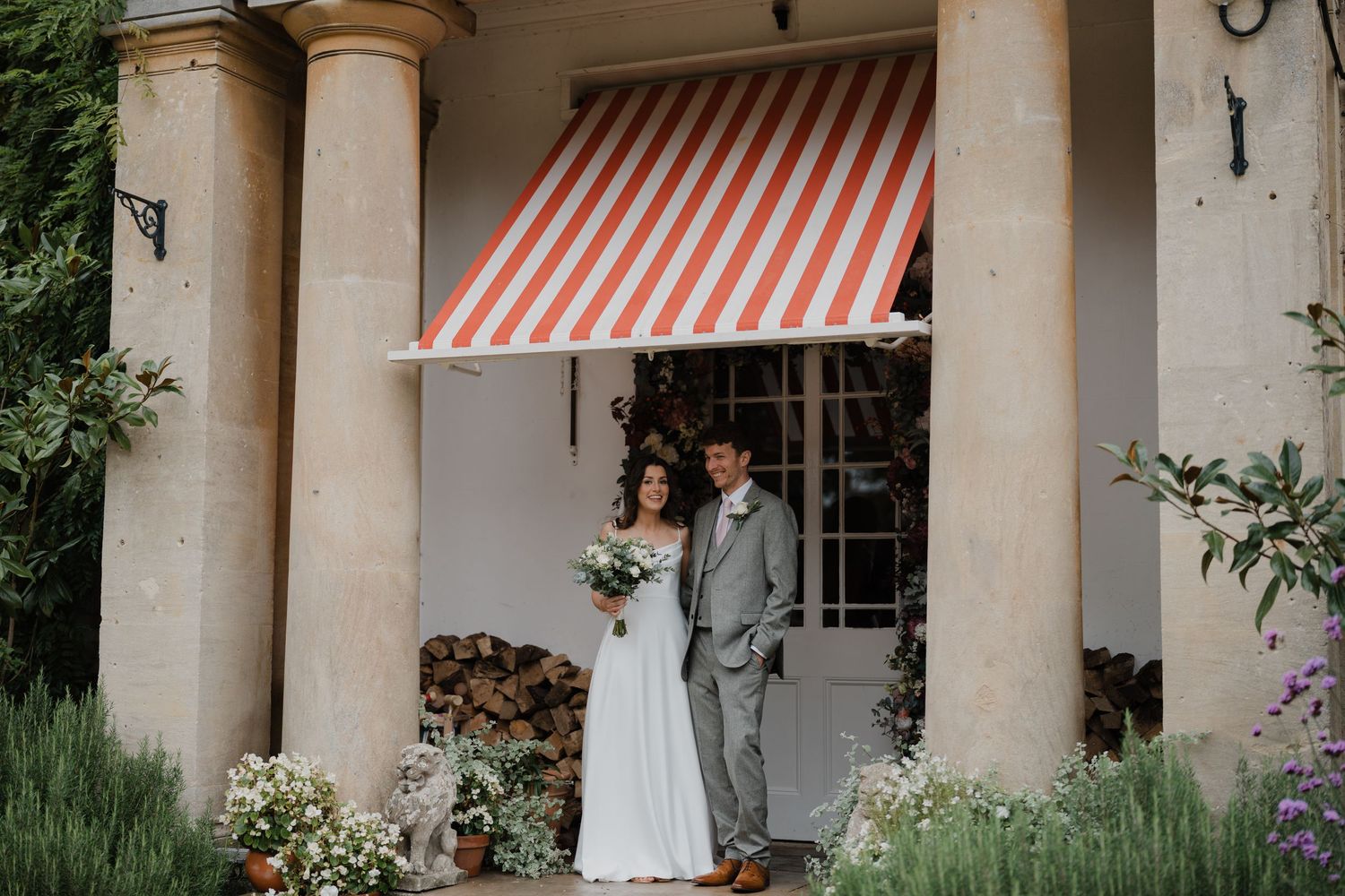 Classical building exterior with columns and red striped awning creates an elegant wedding venue entrance.
