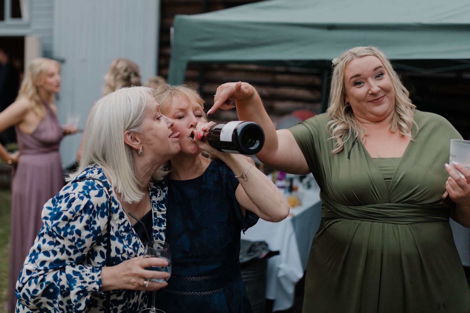 Wedding reception guests dancing and celebrating outdoors under a tent.