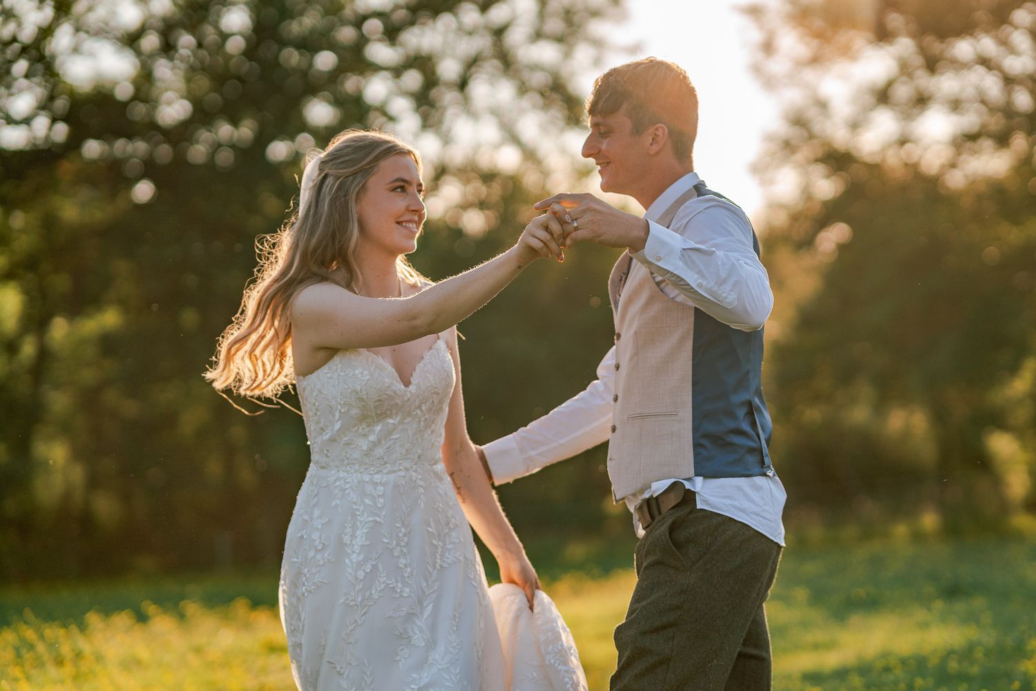 A couple dances together in a field during golden hour.