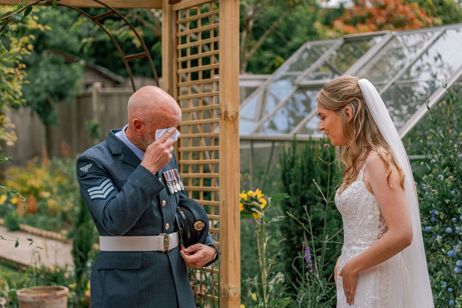 A couple shares romantic moments in a garden setting with wooden pergolas during golden hour.
