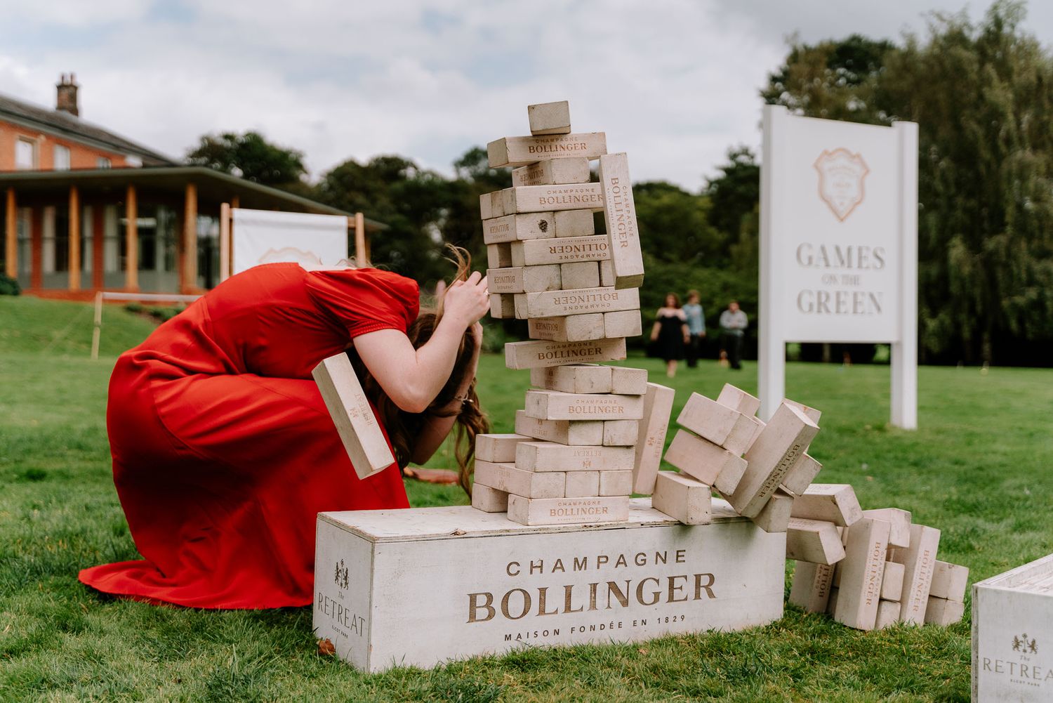 Giant Jenga blocks and champagne boxes arranged on grass at an outdoor event.