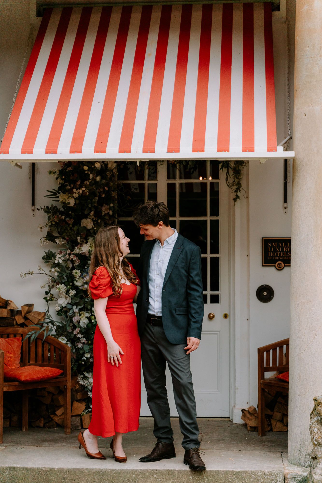 Couple sharing romantic moments under striped red and white awnings at an entrance.
