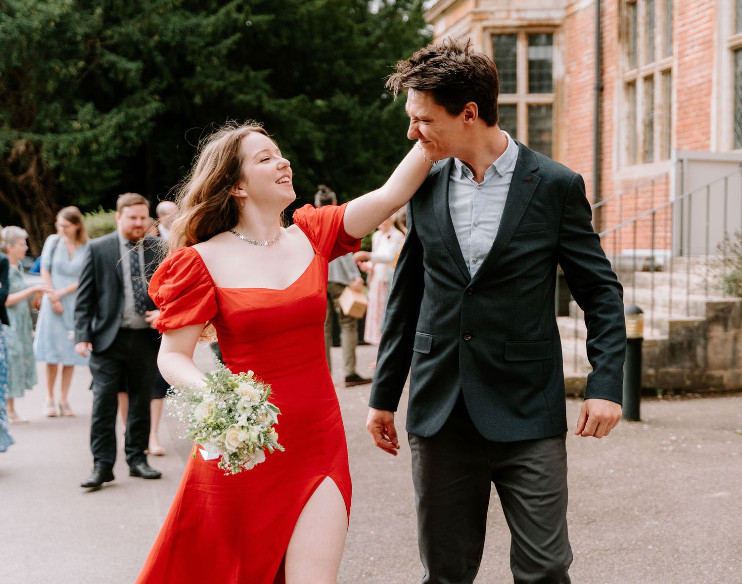 A couple walks together outside a historic brick building.