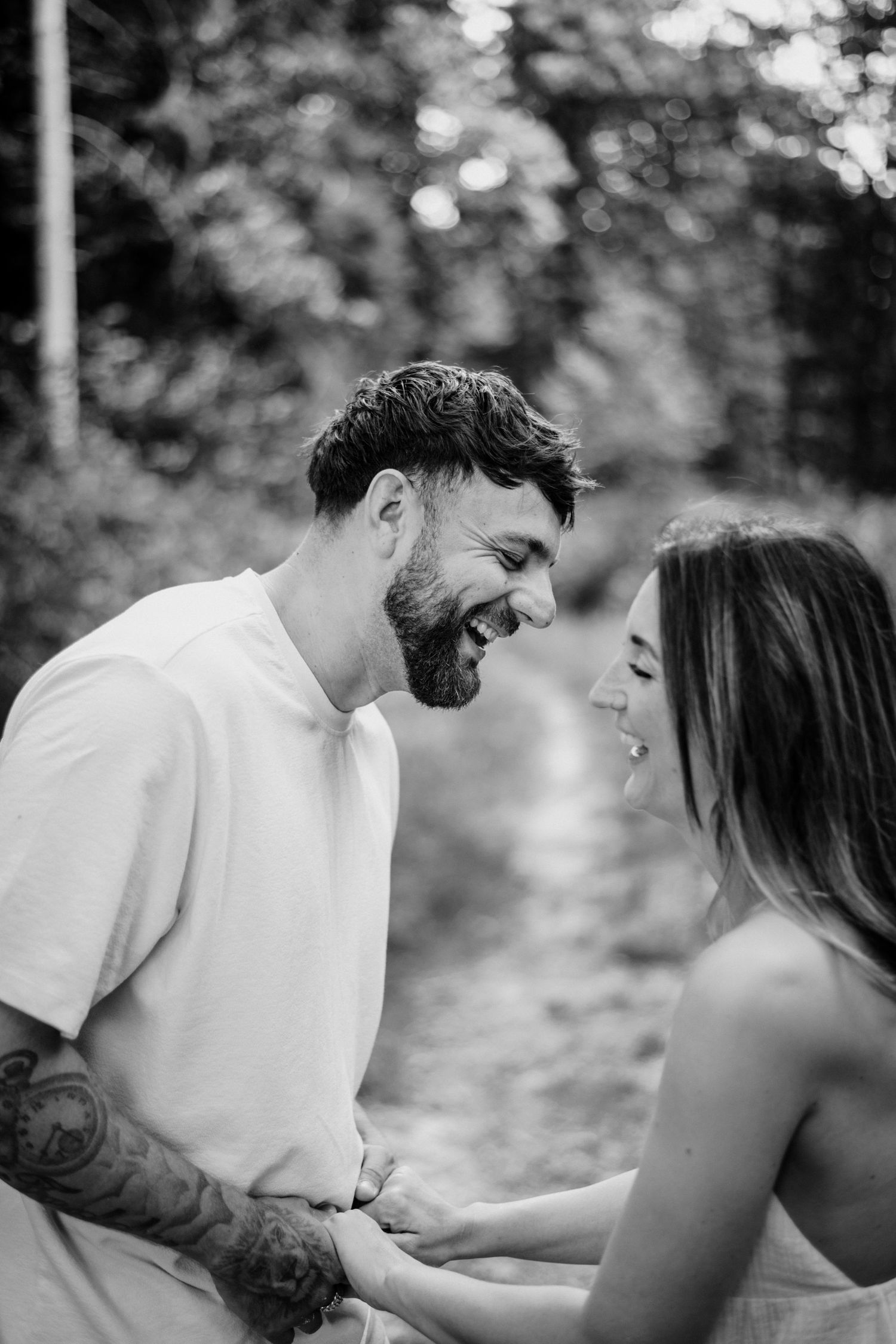 A couple shares a joyful moment together in a black and white outdoor photo sequence.
