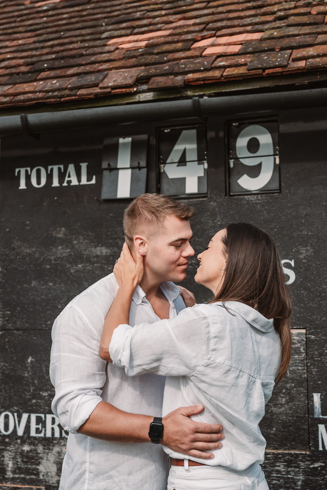 Romantic couple embracing against rustic scoreboard wall with vintage numbers.