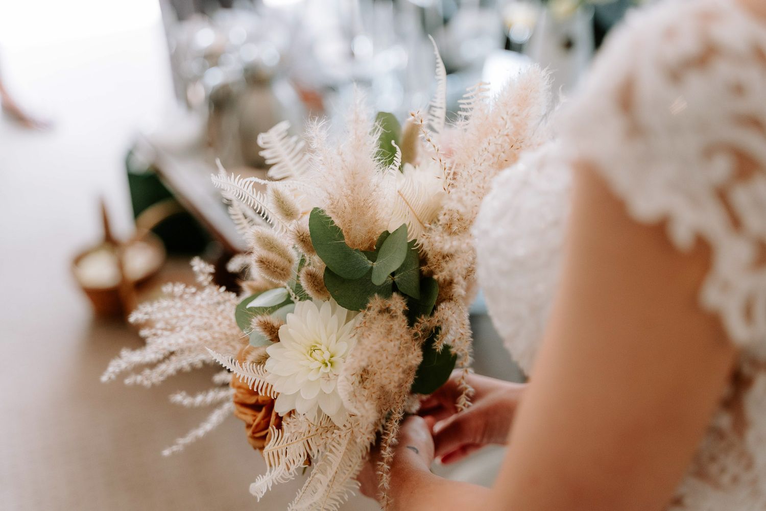 Close-up of ethereal white and blush wedding bouquet with pampas grass and delicate flowers.