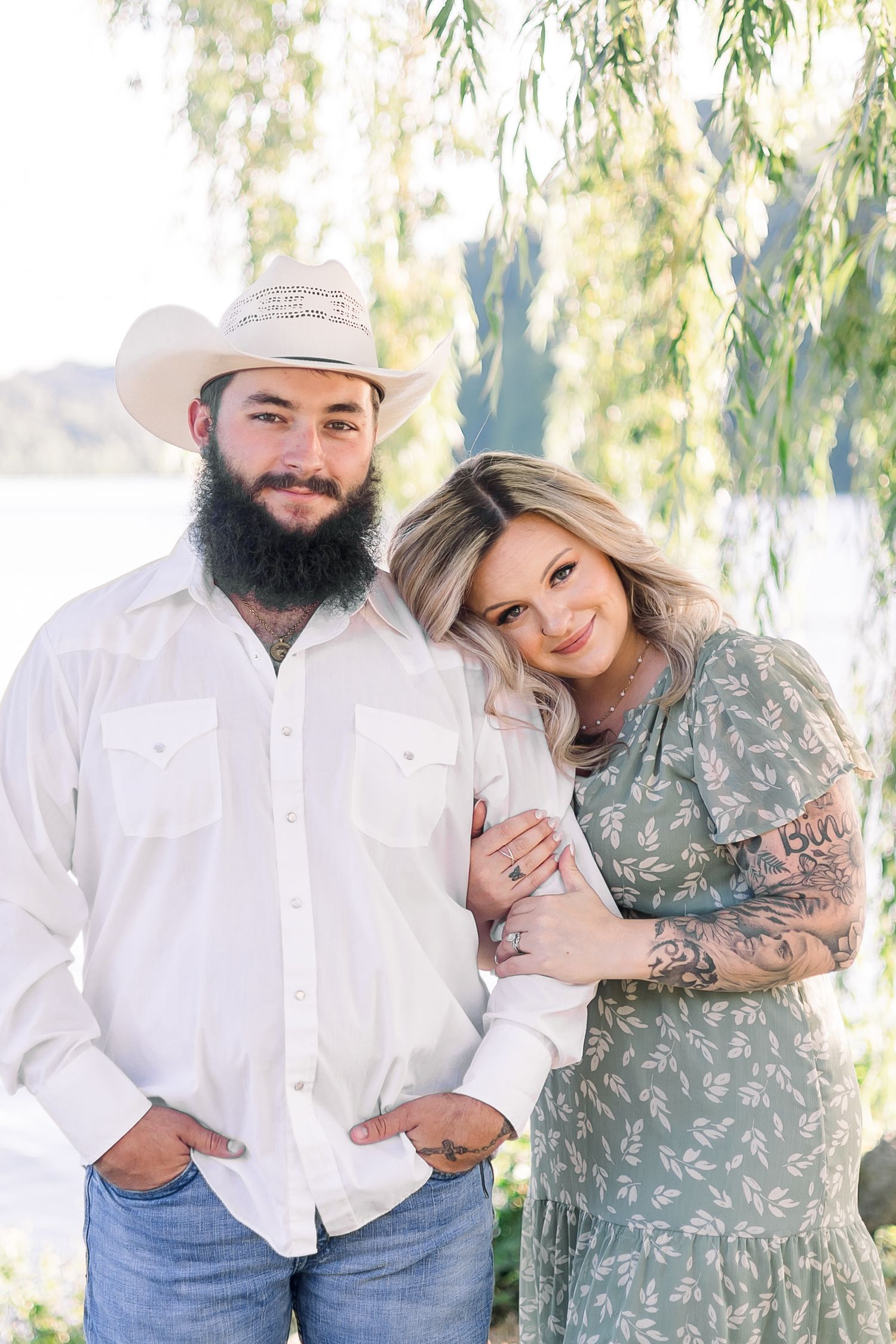 Couple in casual attire sharing tender moments under willow trees.