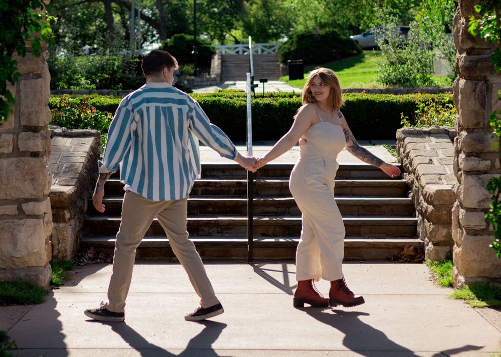 People walking along a sunny garden path with stone columns.