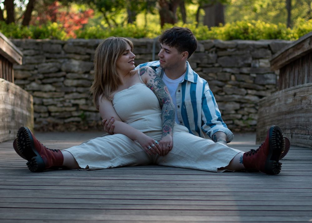A couple relaxes together on a wooden deck surrounded by stone walls.