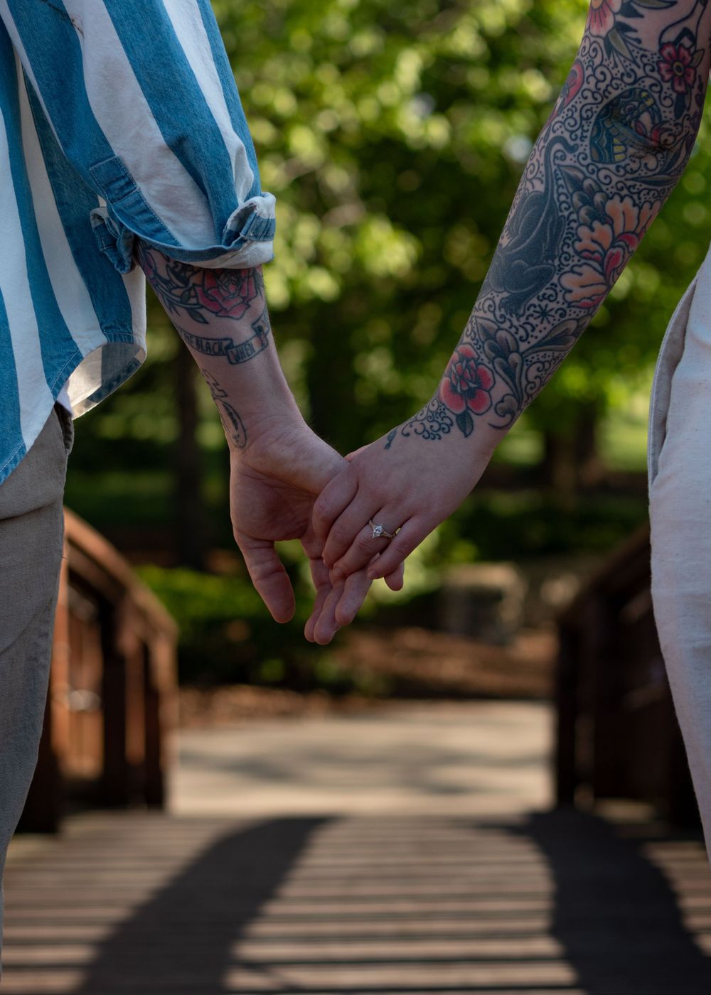 Close-up of hands with colorful tattoo sleeves against blue and white striped fabric.