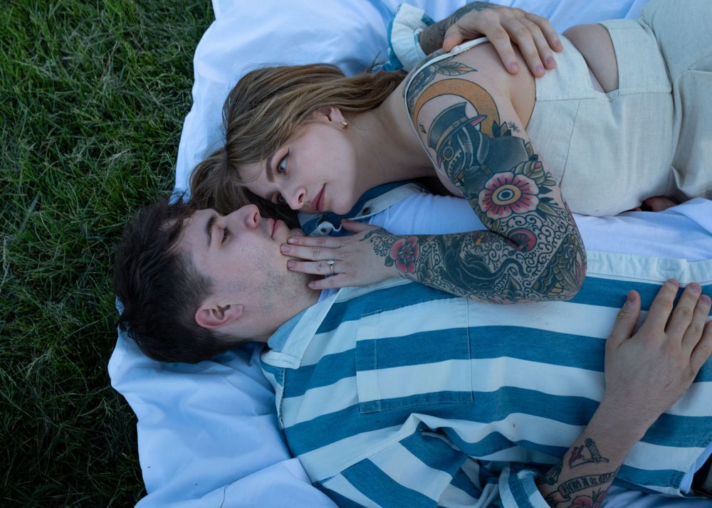 A couple sharing tender moments while lying on grass during a photo session.
