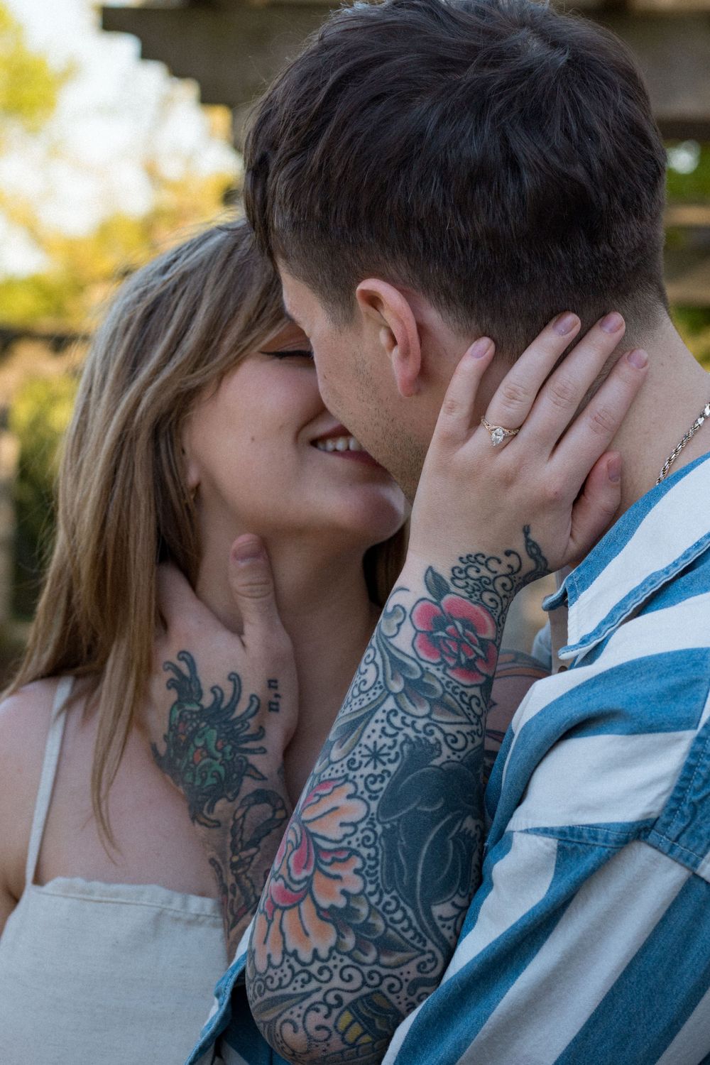 A romantic moment between a couple showing colorful tattoo artwork.