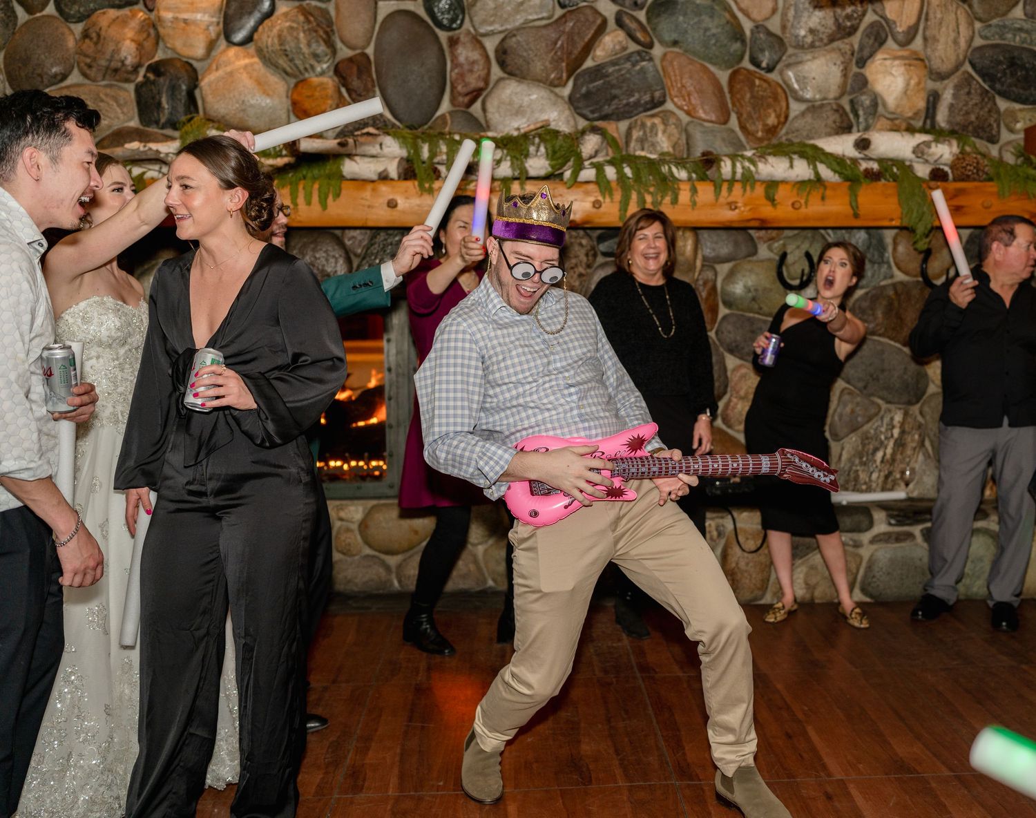 A lively wedding reception scene with partygoers dancing and celebrating on a rustic stone-walled dance floor.