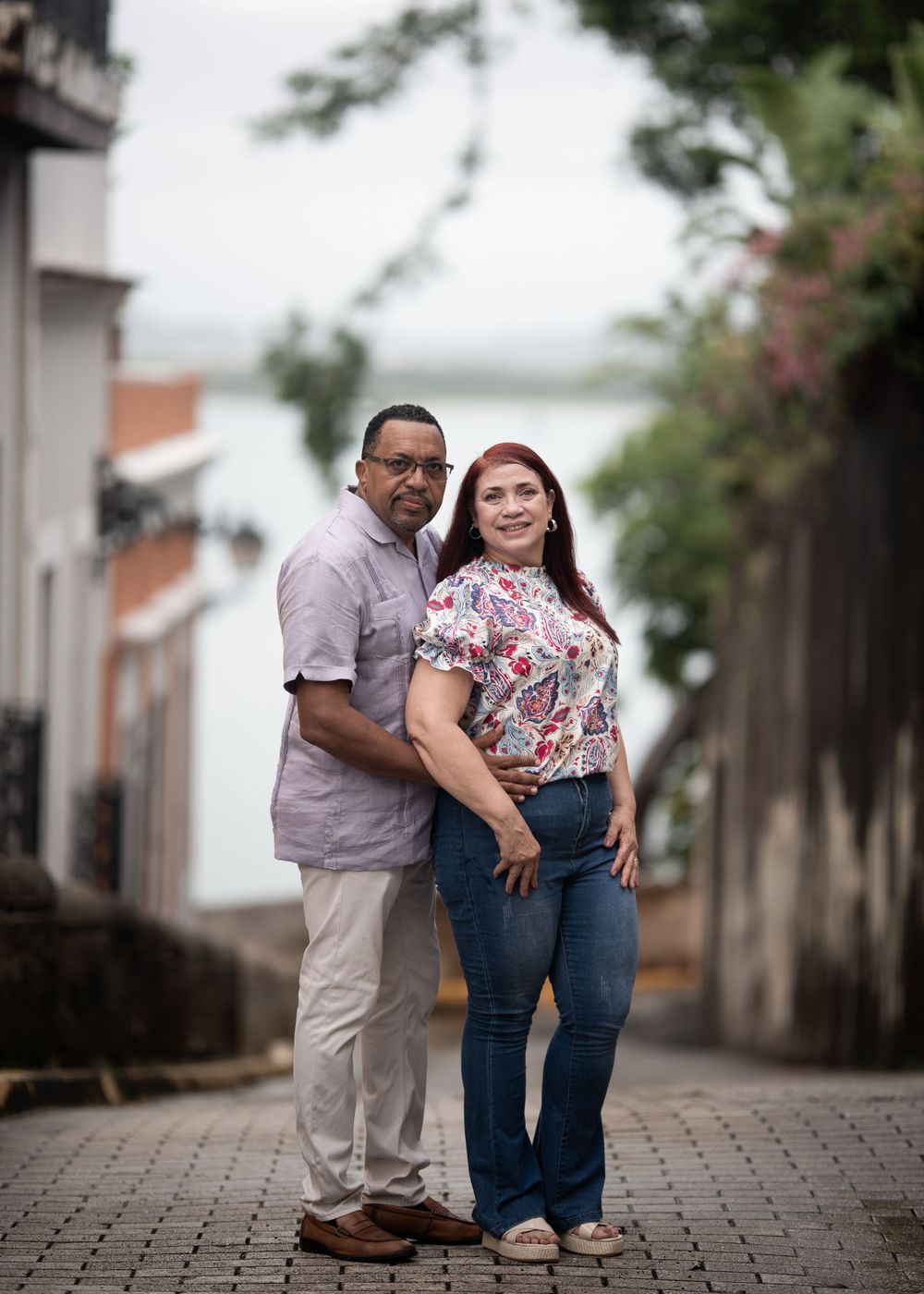 A couple poses together on a cobblestone street in an old town setting.